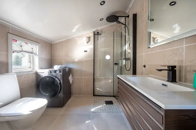 Badet er stilig og moderne, med flislagte vegger og varme i gulv.