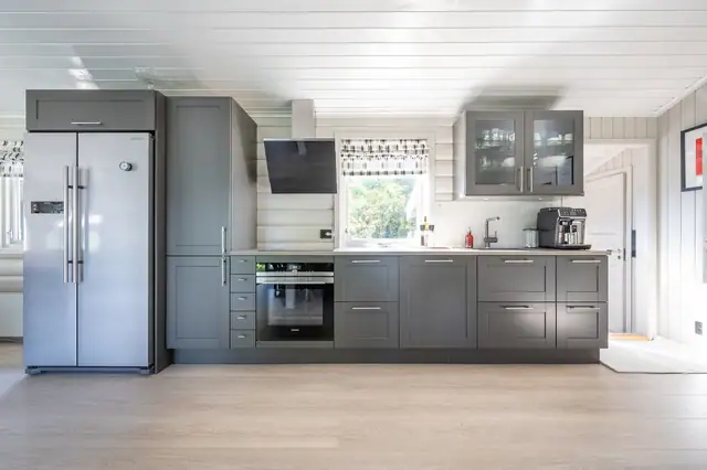 Kjøkkenet er designet med en tidløs estetikk, med grå skapfronter og benkeplate av lys laminat.