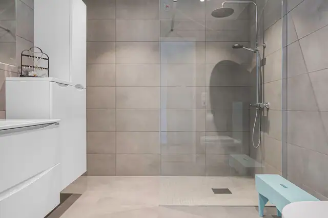 Badet er utstyrt med en romslig dusjnisje med glassvegger. Flisene er tidløse og elegante.
